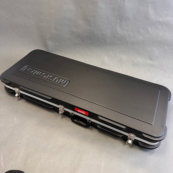 Black hard-shell Music Man guitar case with metal latches and handle on gray background