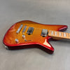 Electric guitar with metallic orange and red burst finish, chrome hardware, two humbucker pickups, and maple fretboard with block inlays on gray background