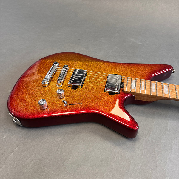 Electric guitar with metallic orange and red burst finish, chrome hardware, two humbucker pickups, and maple fretboard with block inlays on gray background