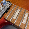 Close-up of electric guitar fretboard with pearl inlays, chrome frets, and orange sparkle finish body near pickup and strings.