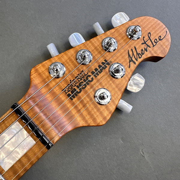 Maple Music Man Albert Lee electric guitar headstock with pearloid tuning pegs and inlaid fretboard on gray background