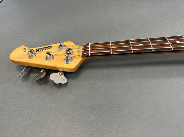 Music Man StingRay bass guitar headstock with tuning pegs and rosewood fretboard on gray background
