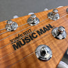 Ernie Ball Music Man guitar headstock close-up with tuning pegs and strings on natural wood finish