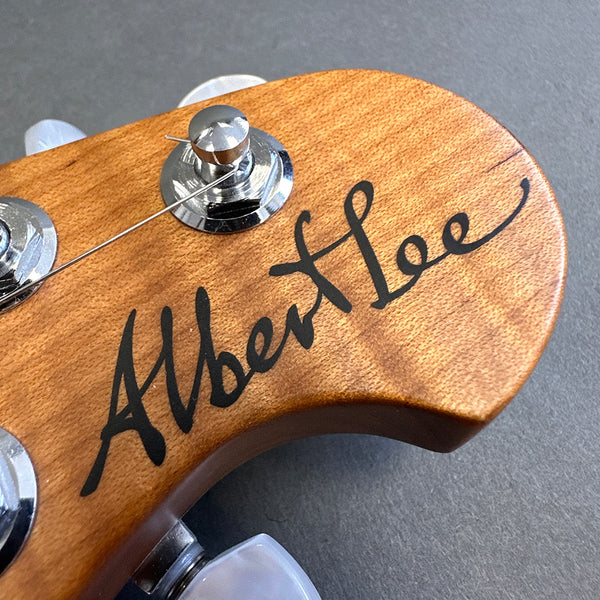 Close-up of Albert Lee signature on wooden guitar headstock with tuning peg and string visible