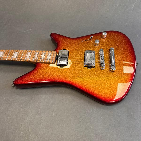 Electric guitar with sparkling red to orange sunburst finish, dual humbucker pickups, chrome bridge, and maple neck with rectangular inlays on gray background