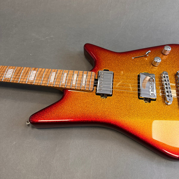 Electric guitar with red to orange sunburst finish and maple neck with block inlays on fretboard