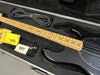 Black electric bass guitar with maple neck and fretboard in black padded hard case with guitar strap, polishing cloth, and tuning key accessories