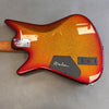 Back view of electric guitar with metallic red and orange sunburst finish, featuring neck plate, signed black control cavity cover, and battery compartment.