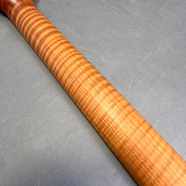 Close-up of guitar neck made from flame maple wood with prominent curly grain pattern on gray background