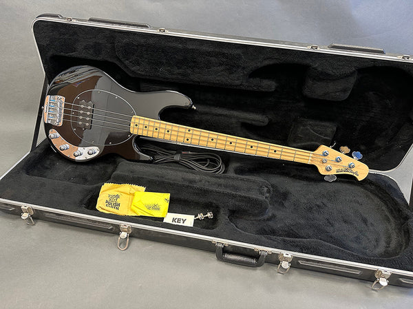 Ernie Ball Music Man StingRay 4-string electric bass guitar with maple neck and black body in black padded hard case with polishing cloth, guitar cable, and case key.