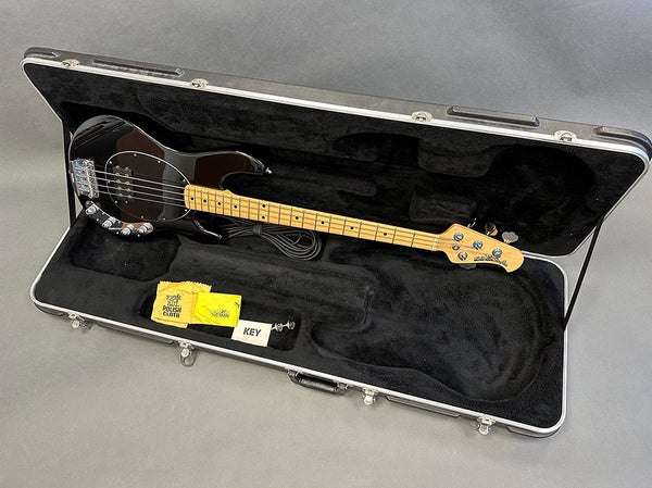 Black electric bass guitar with maple neck in open hard case with polishing cloth, strap, and key inside, Coffee House Guitars product listing image