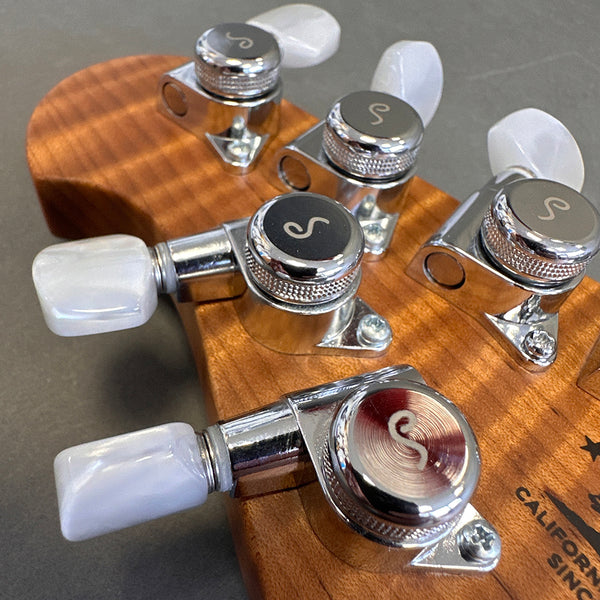 Close-up of chrome tuning pegs with white pearloid buttons on natural wood guitar headstock from Coffee House Guitars