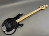 Black electric bass guitar with maple neck and chrome hardware on gray background