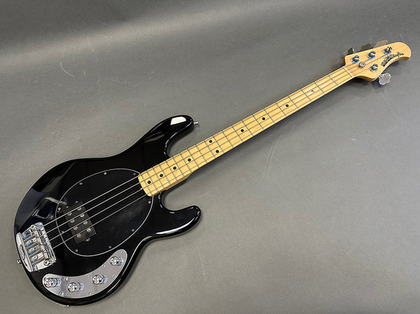 Black electric bass guitar with maple neck and chrome hardware on gray background