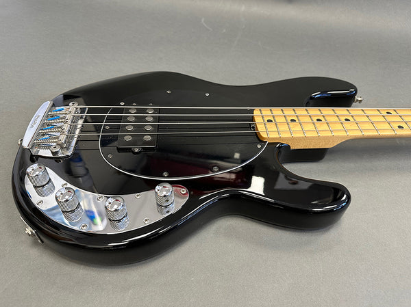 Black electric bass guitar with maple neck and chrome hardware on grey background