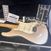 Fender Stratocaster electric guitar in silver metallic finish with maple neck, displayed in a black hard case with Fender owner's manual and registration cards.