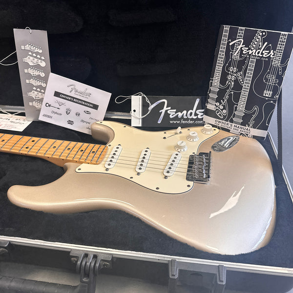 Fender Stratocaster electric guitar in silver metallic finish with maple neck, displayed in a black hard case with Fender owner's manual and registration cards.