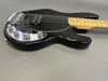 Black electric bass guitar with maple neck, chrome control knobs, and black pickguard on gray background