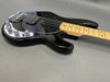 Black electric bass guitar with maple neck and chrome hardware on gray background