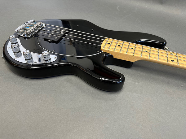 Black electric bass guitar with maple neck and chrome hardware on gray background