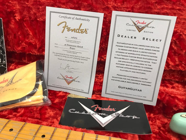 Fender Custom Shop certificate of authenticity and dealer select documents on red velvet background with guitar neck and Fender cleaning cloth.