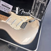 Fender Stratocaster electric guitar in metallic finish with maple neck, displayed in hard case with Fender owner's manual and registration card.