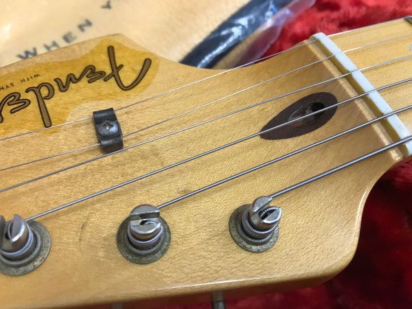 Close-up of vintage Fender guitar headstock with tuning pegs, strings, and nut on maple wood neck