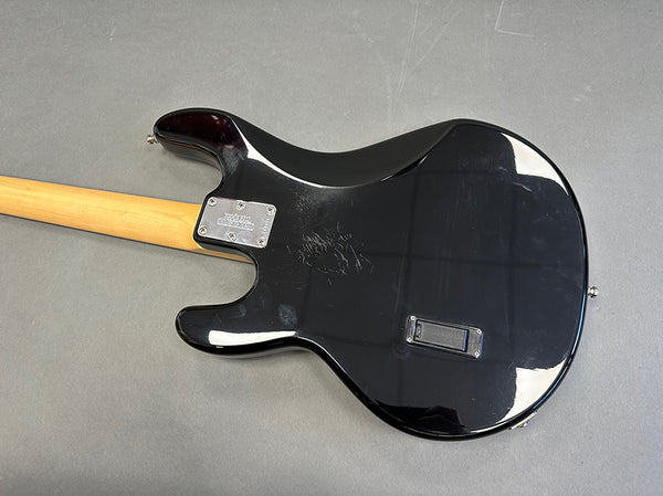 Black electric guitar body with visible scratches and a light wood neck, showing the back side on a gray surface, Coffee House Guitars product listing.