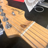 Close-up of Fender Stratocaster electric guitar headstock with tuning pegs and strings on a black surface