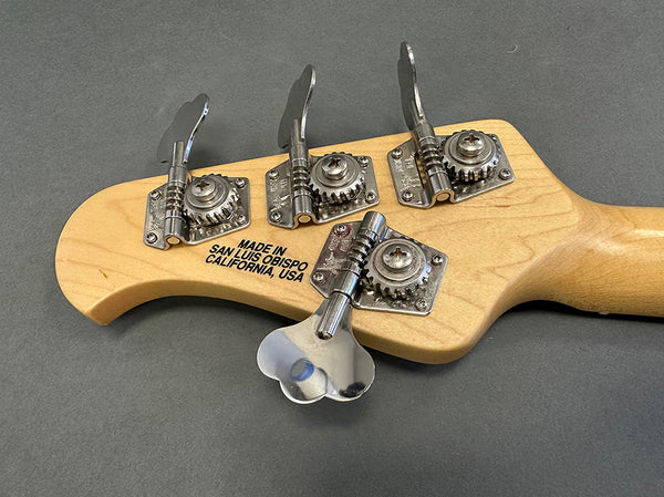 Close-up of maple guitar headstock with four chrome tuning pegs and "Made in San Luis Obispo California USA" stamp on the back of the neck