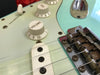 Close-up of volume knob, pickup, and bridge on a light blue electric guitar with vintage-style components and rusted bridge saddles at Coffee House Guitars.