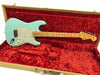 Fender Stratocaster electric guitar in seafoam green with maple neck and vintage-style pickups, displayed inside red plush-lined tweed hard case.