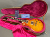Gibson Les Paul electric guitar with sunburst flame maple top in open vintage hardshell case with pink plush interior and Gibson warranty tags