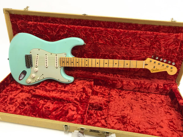 Fender Stratocaster electric guitar in seafoam green with maple neck and vintage-style pickups, displayed inside red plush-lined tweed hard case.