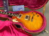 Gibson Les Paul electric guitar with sunburst flame maple top in vintage hardshell case with pink plush interior and Gibson USA tags and warranty card.