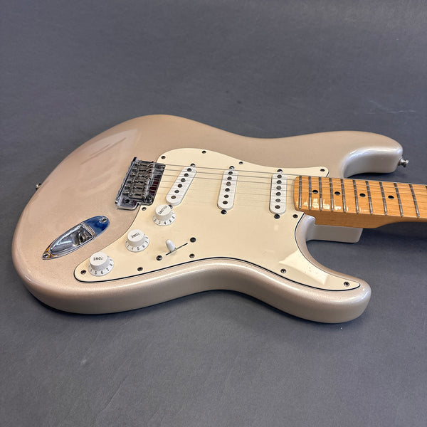 Light gold electric guitar with maple neck and white pickguard showing body and partial neck on gray background