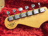 Close-up of Fender Custom Shop Limited Edition electric guitar headstock with six tuning pegs on red plush guitar case lining