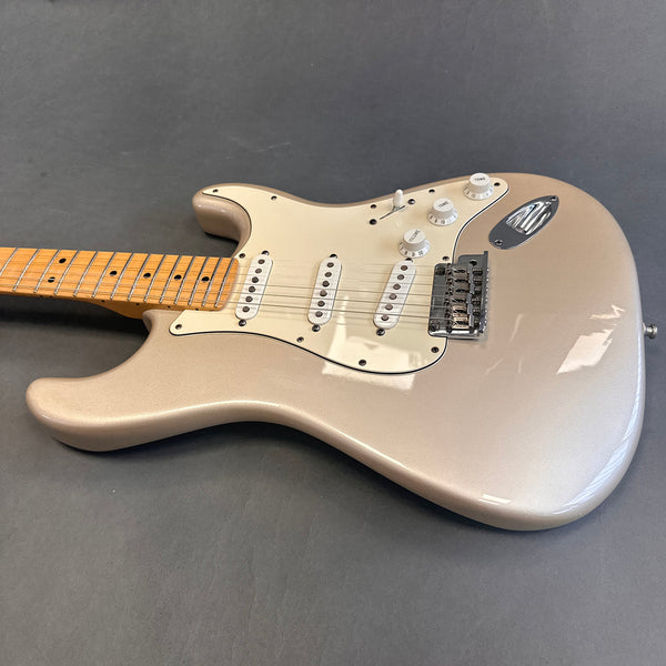 Electric guitar with metallic silver body, white pickguard, three single-coil pickups, maple neck, and tone and volume knobs on a gray background