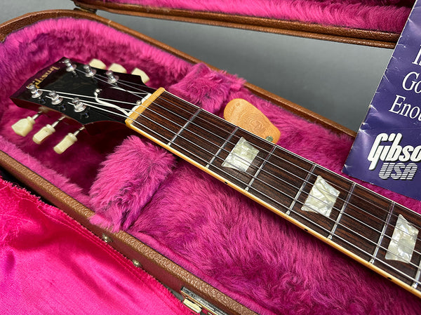 Close-up of Gibson guitar headstock and rosewood fretboard with pearl block inlays in purple plush-lined guitar case