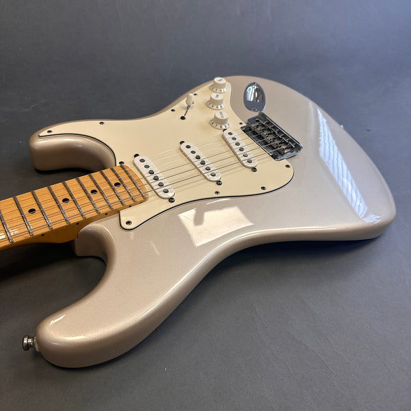 Electric guitar with pearl white finish, maple neck, and three single-coil pickups on a gray background