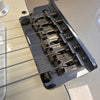 Close-up of Fender guitar bridge with six strings and individual metal saddles on a cream electric guitar body