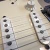 Close-up of vintage white electric guitar pickups and volume knob with six strings on cream guitar body