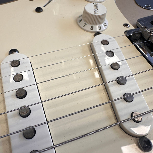 Close-up of vintage white electric guitar pickups and volume knob with six strings on cream guitar body