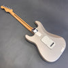 Back view of metallic silver electric guitar with maple neck and chrome tuning pegs on gray background