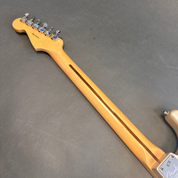 Back view of maple neck and headstock with chrome tuning pegs on electric guitar against dark background