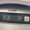 Close-up of digital scale display showing guitar weight 3.592 kilograms on DYMO scale with tare and hold buttons visible