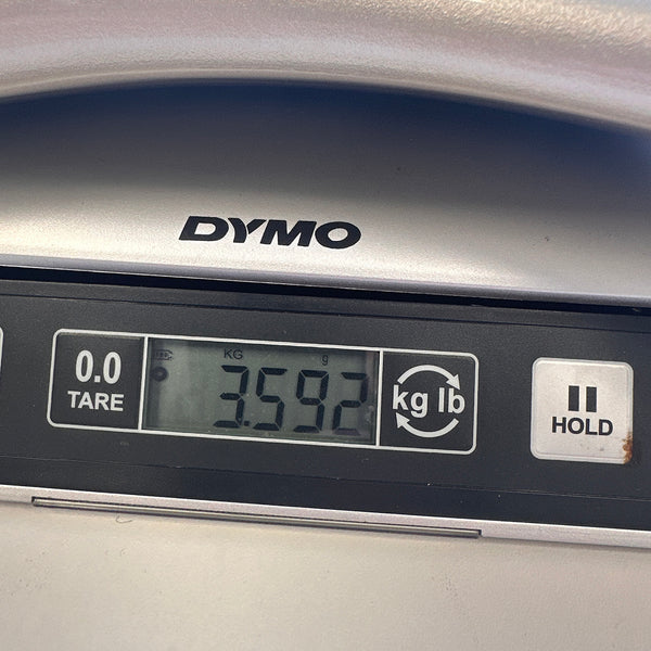 Close-up of digital scale display showing guitar weight 3.592 kilograms on DYMO scale with tare and hold buttons visible
