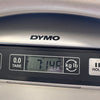 Close-up of DYMO digital scale showing weight measurement of 7 pounds 14.6 ounces for guitar product at Coffee House Guitars