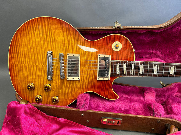 Vintage sunburst electric guitar with humbucker pickups in an open hard case with pink interior lining
