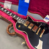 Gibson electric guitar with black finish, three gold humbucker pickups, toggle switch, and black control knobs inside a brown hard case lined with pink plush interior